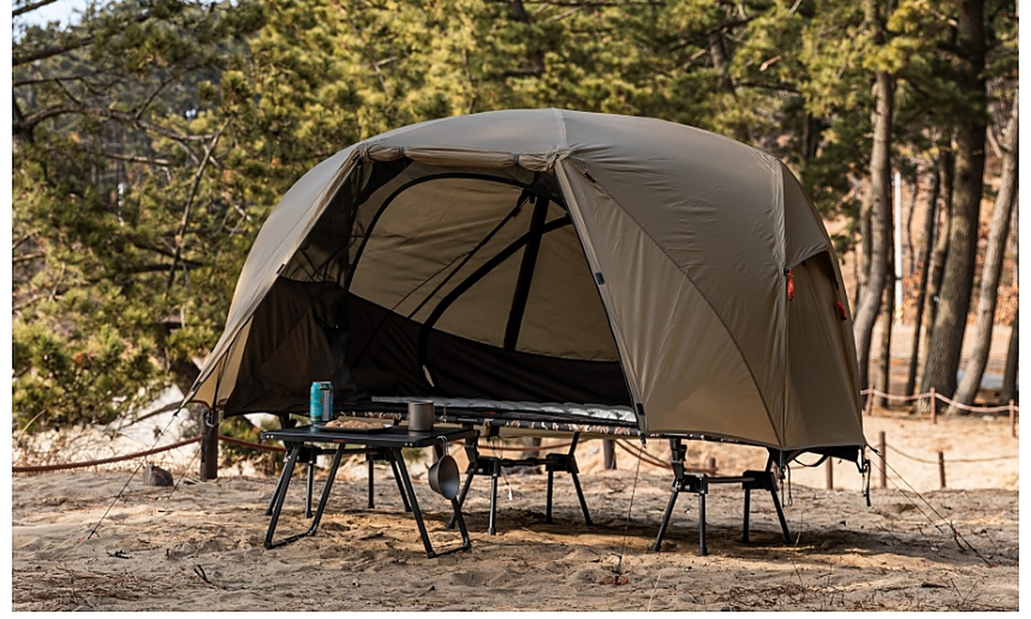 Base Cot Tent pitched at a forest beach campsite, wide view