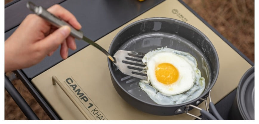 Tongs flipping a fried egg in a camp pan