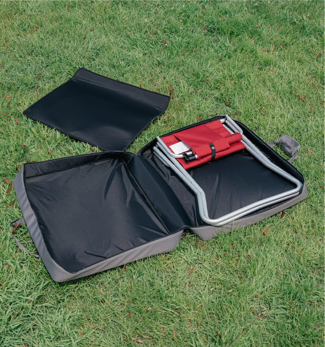 Open CORDURA FD Chair Case with one folded chair inside and the removable centre partition on the grass