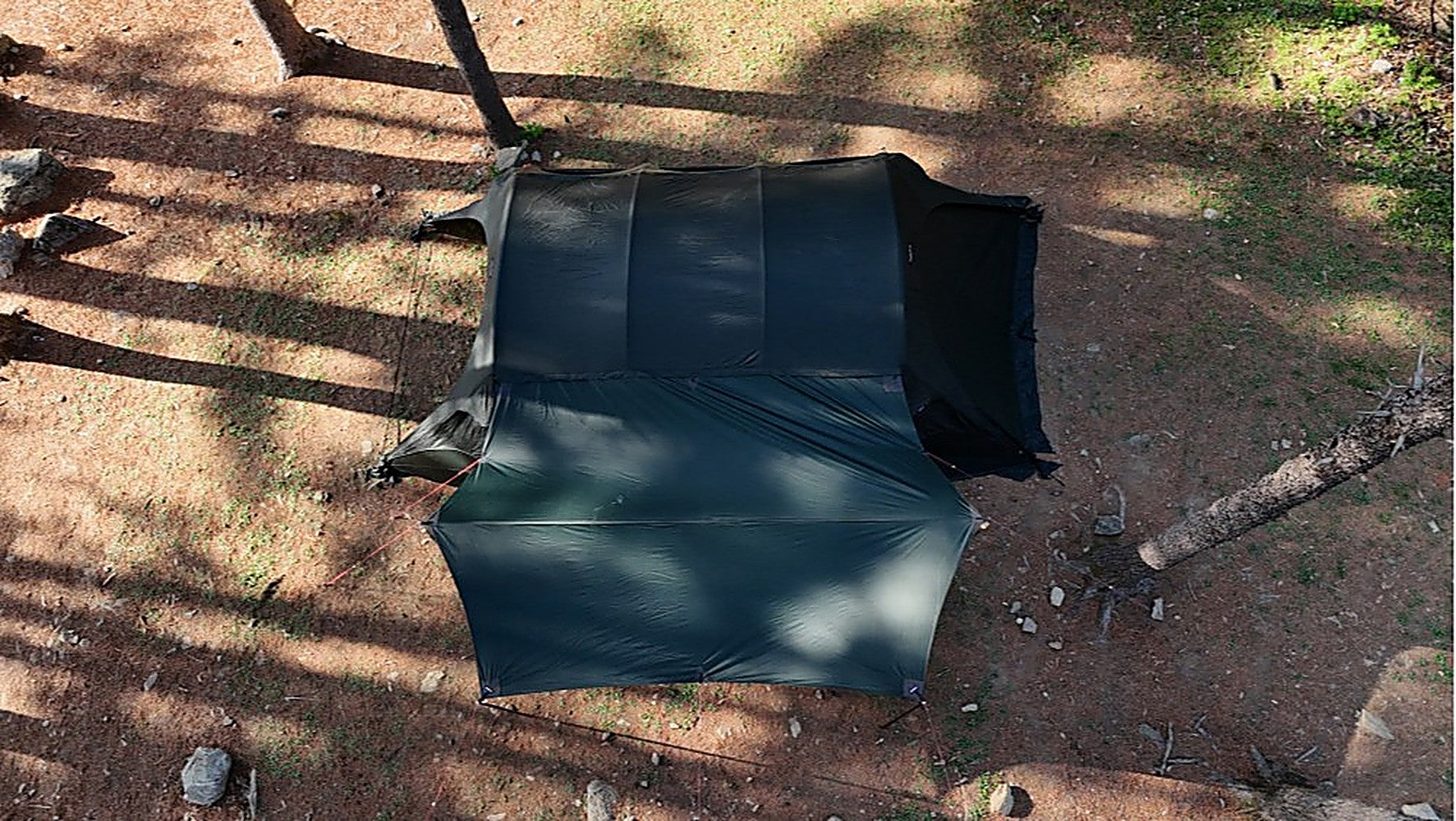 Aerial view of Gopamir T720+ Side Tarp in black-coated dark green extending from a tent at a forest campsite