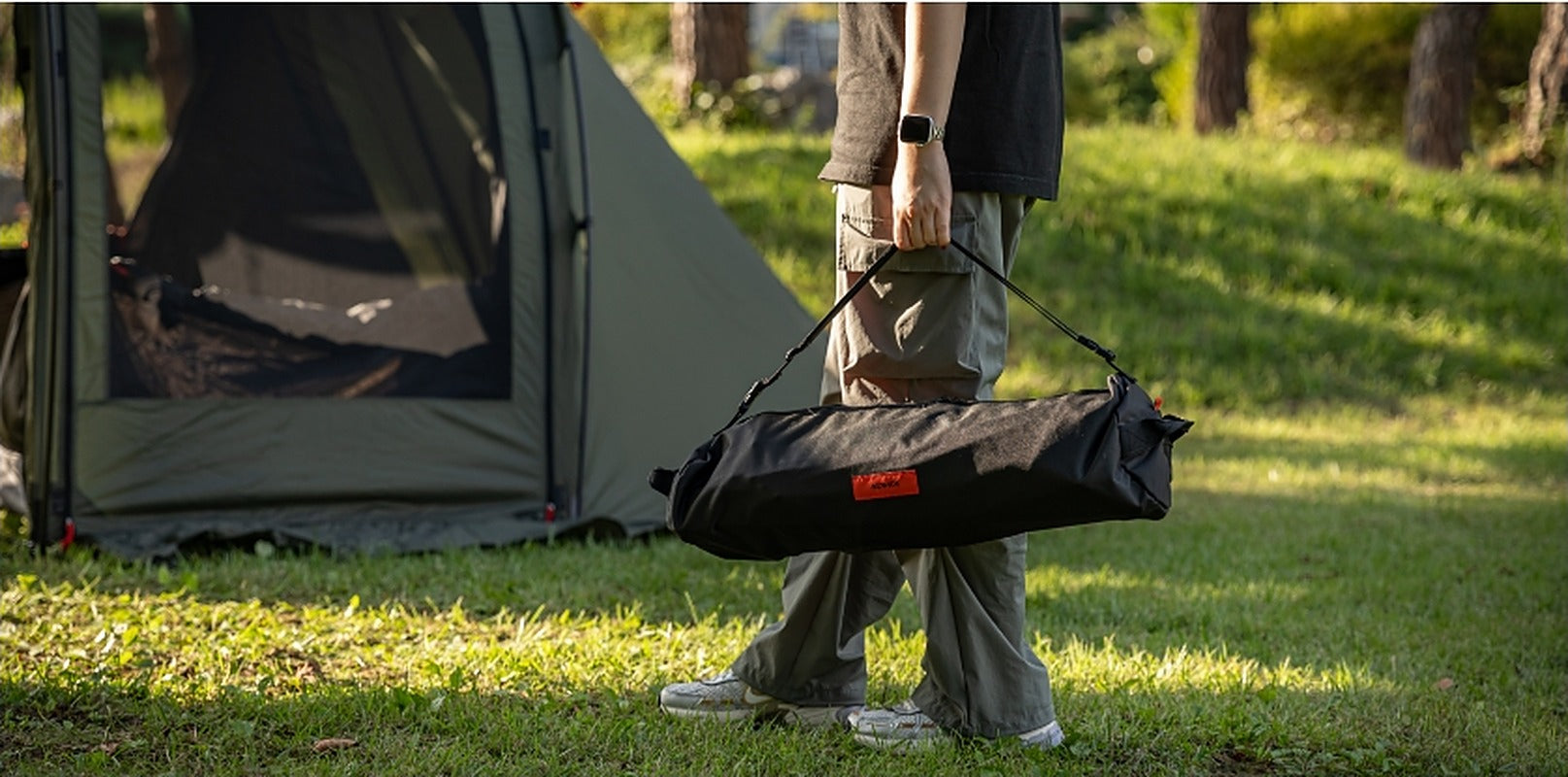 Walking with the packed cot carry case at the campsite