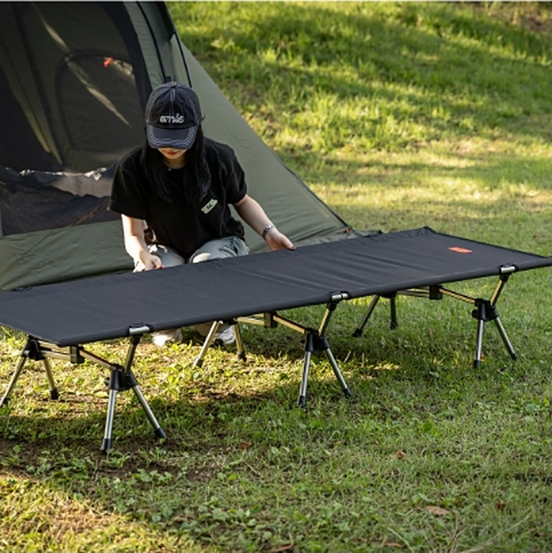 Folding down the cot next to a tent