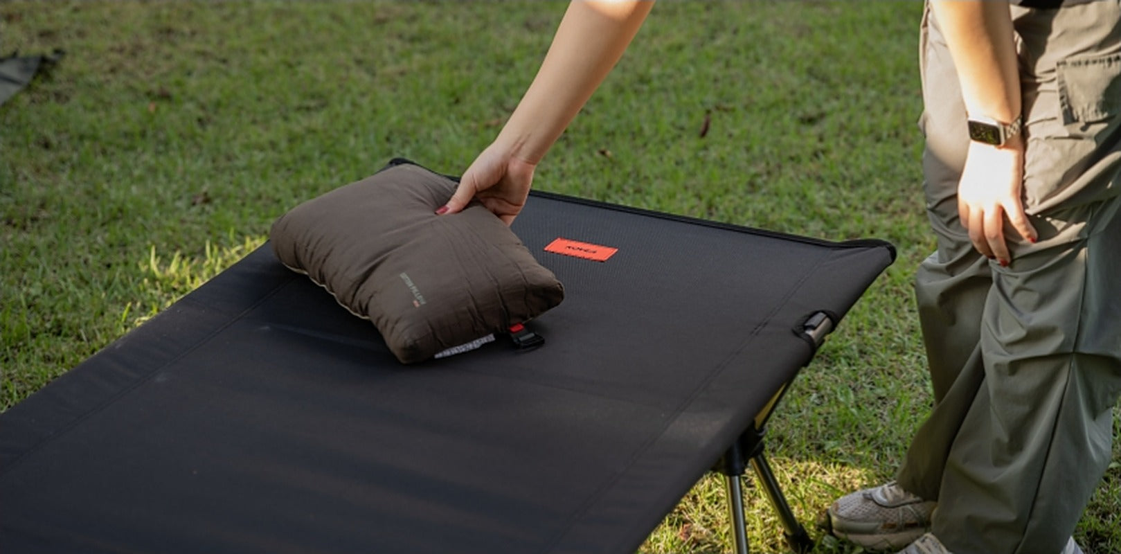 Placing a pillow on the cot at the campsite