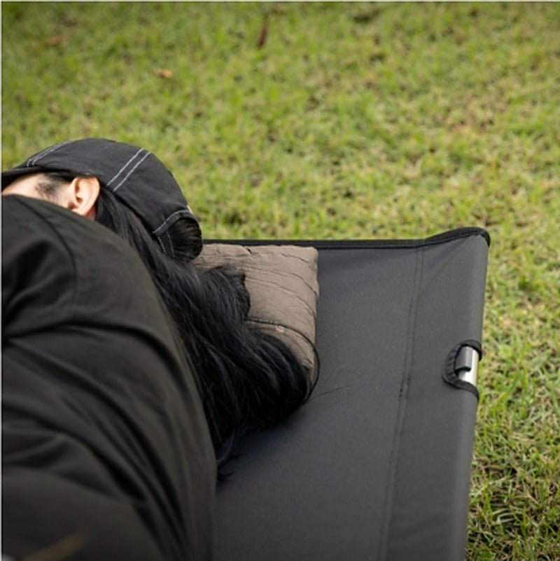 Person resting on the cot with a pillow