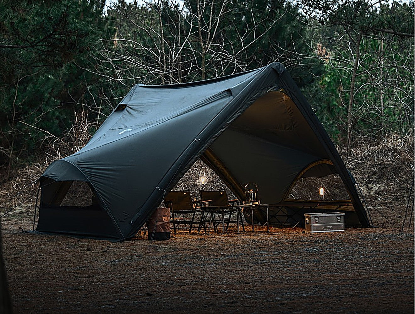 Wide evening shot of Super Position with the MGX-600 TPU Door section, camp furniture and aluminum box beneath the canopy