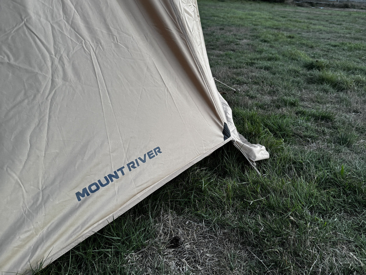 Hem of the Natural rainfly with the Mount River wordmark and a pegged corner guy line.