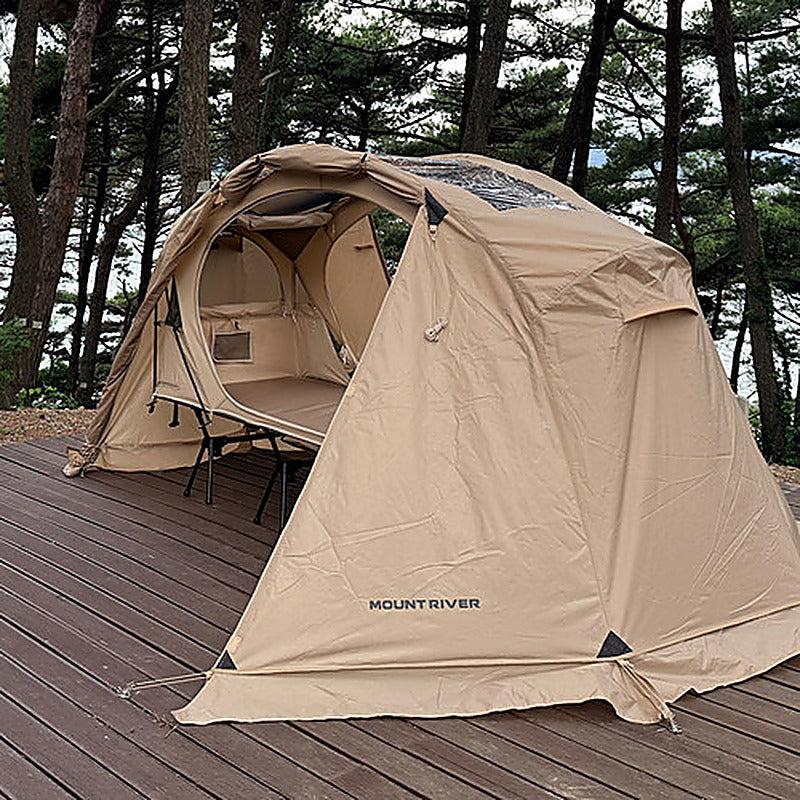 Rainfly closed over the cot tent on a wooden deck in a pine forest (tent and cot sold separately).