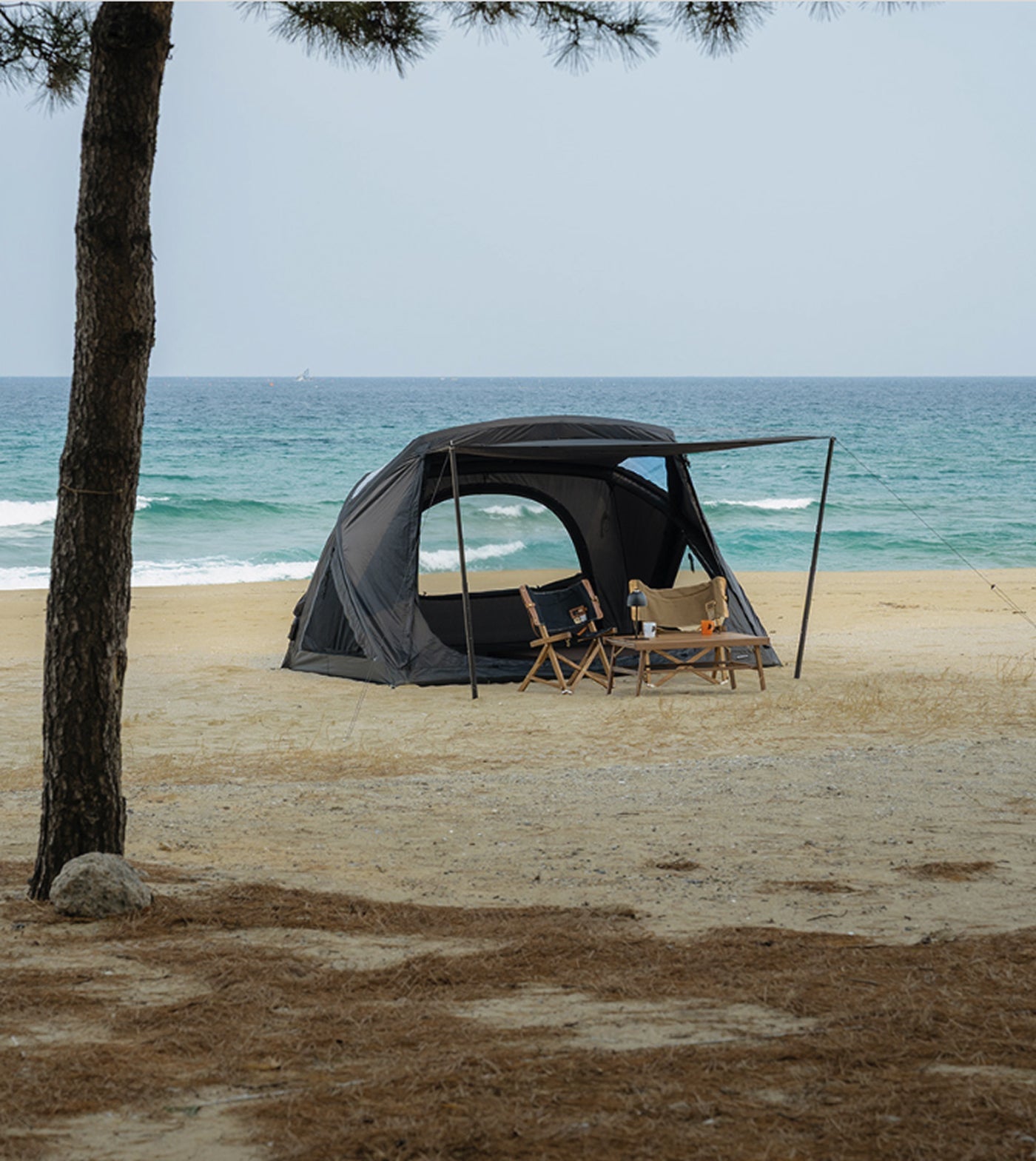 theEarth GEO AIR4 Tent, Black, side profile with extended awning on a beach