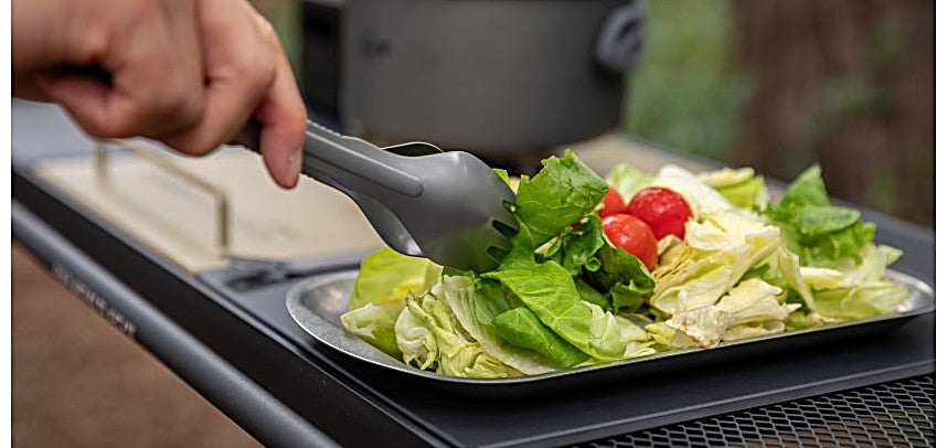 Tongs picking up salad at a camp table