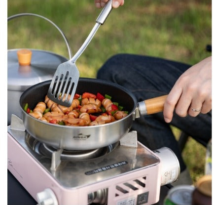 Stirring food in the fry pan on a portable gas stove using the wood handle
