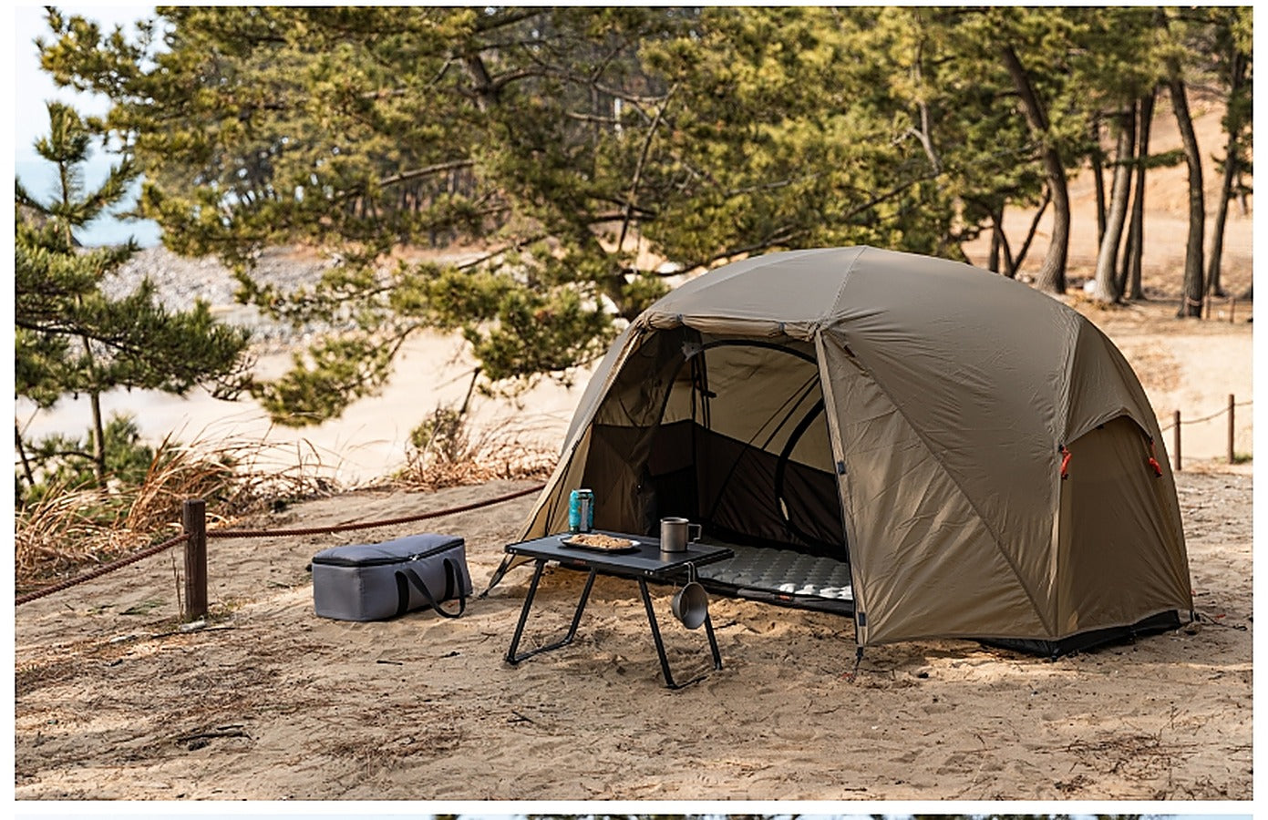 Base Cot Tent pitched at a beach campsite next to a camp table