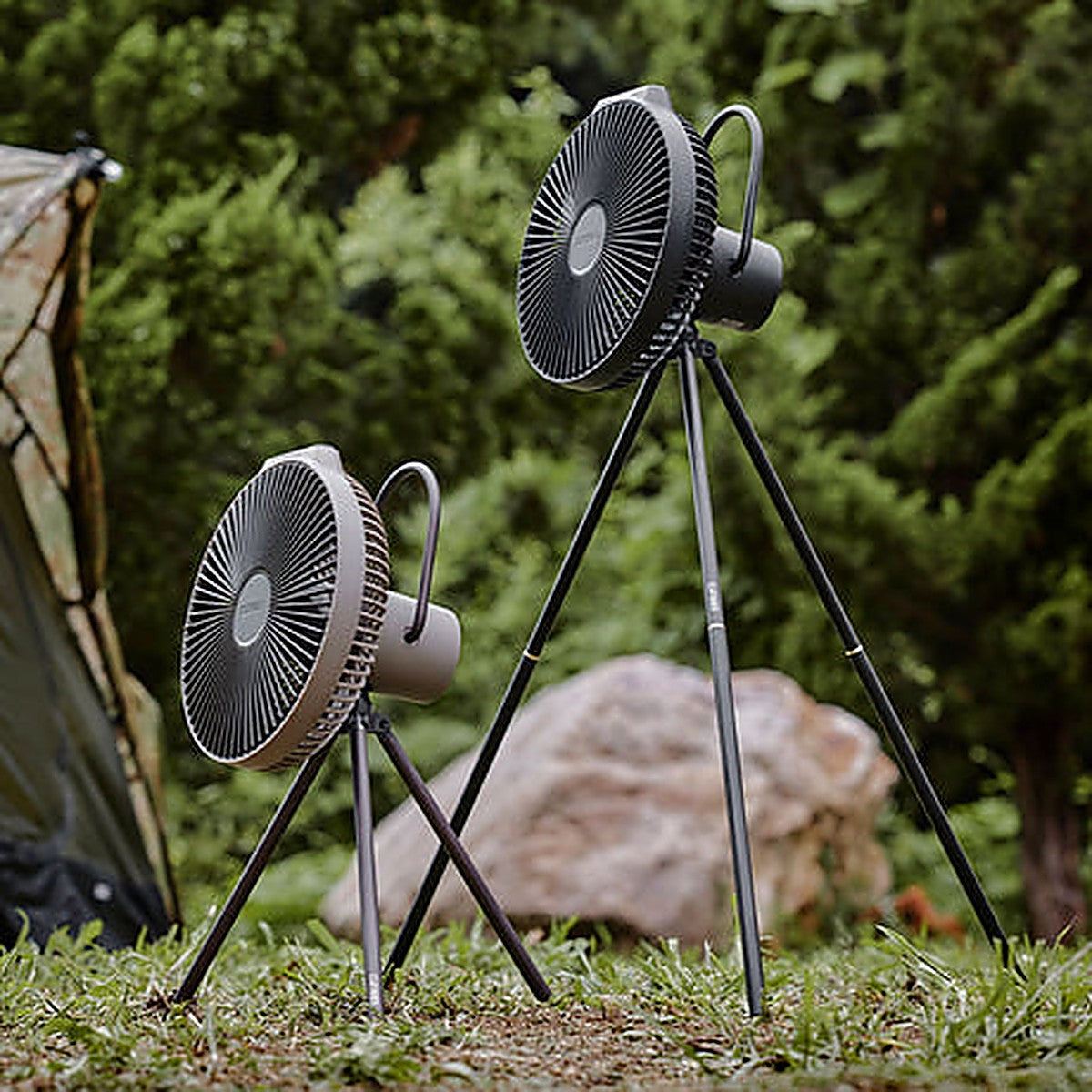 Two V1040 fans on tripods at a grassy campsite