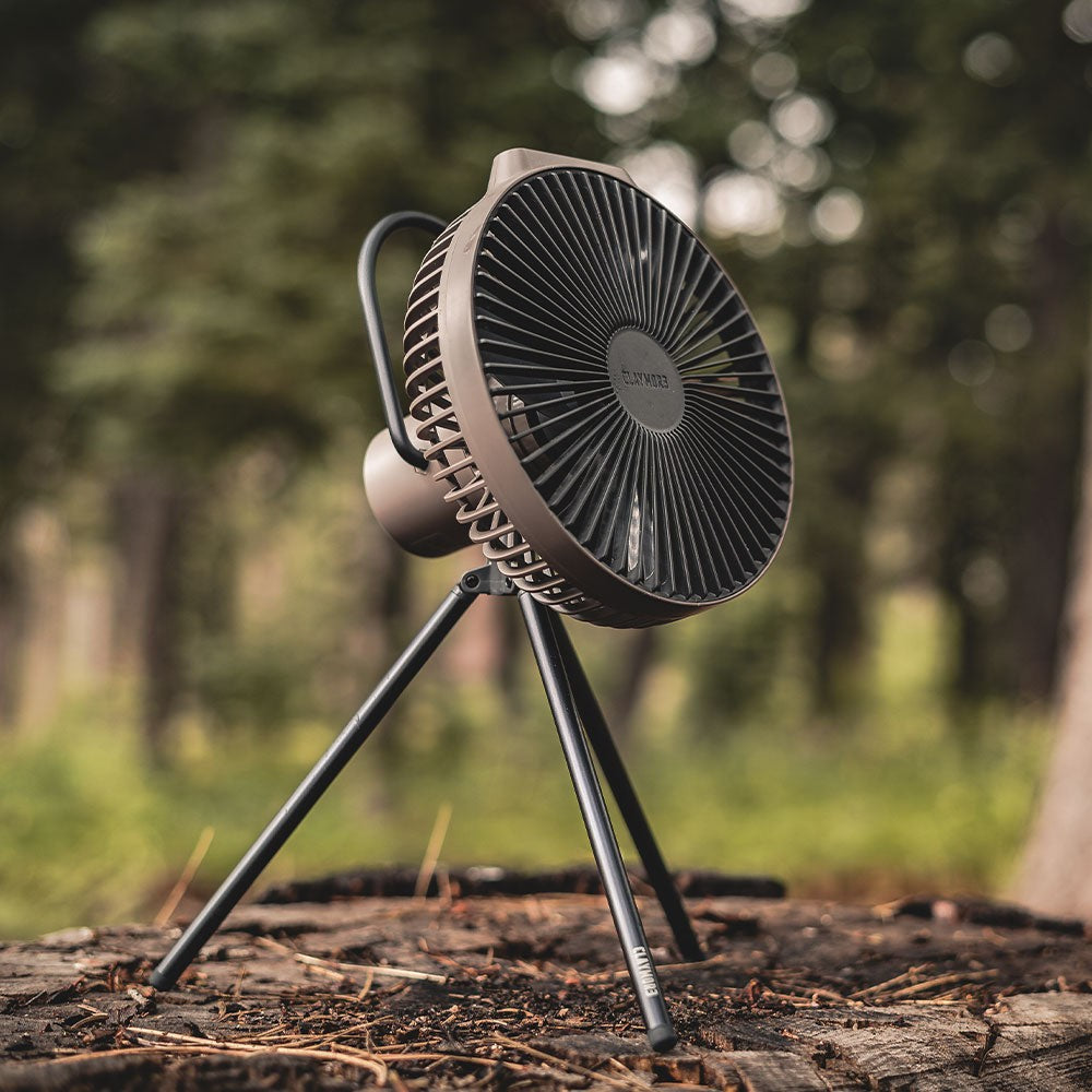 CLAYMORE V600+ rechargeable fan running cordless on a tree stump at a forest campsite