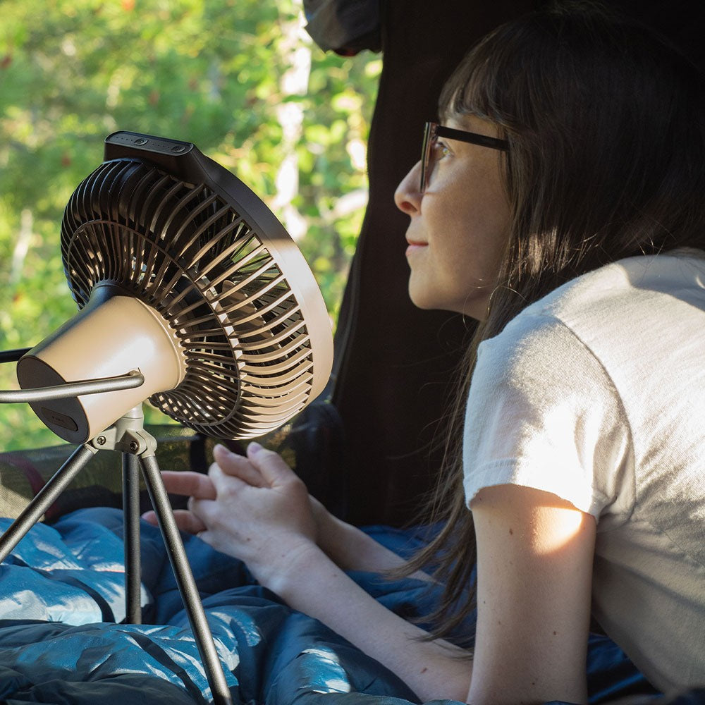 Camper lying in a tent with the V600+ fan running on its tripod, timer set for sleep