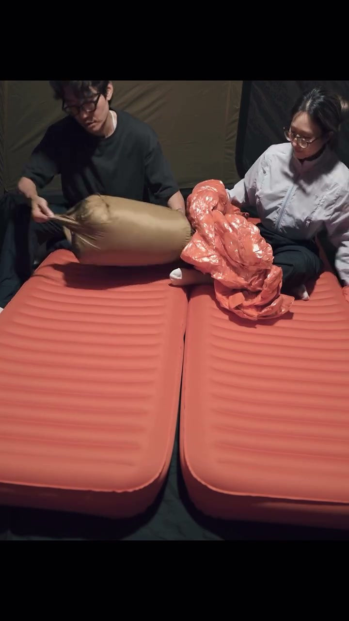 Field-tester video still — campers unpacking DEOS camp comforters over inflatable mats in a tent