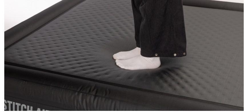 Person standing on the air mat without sinking, demonstrating firm support