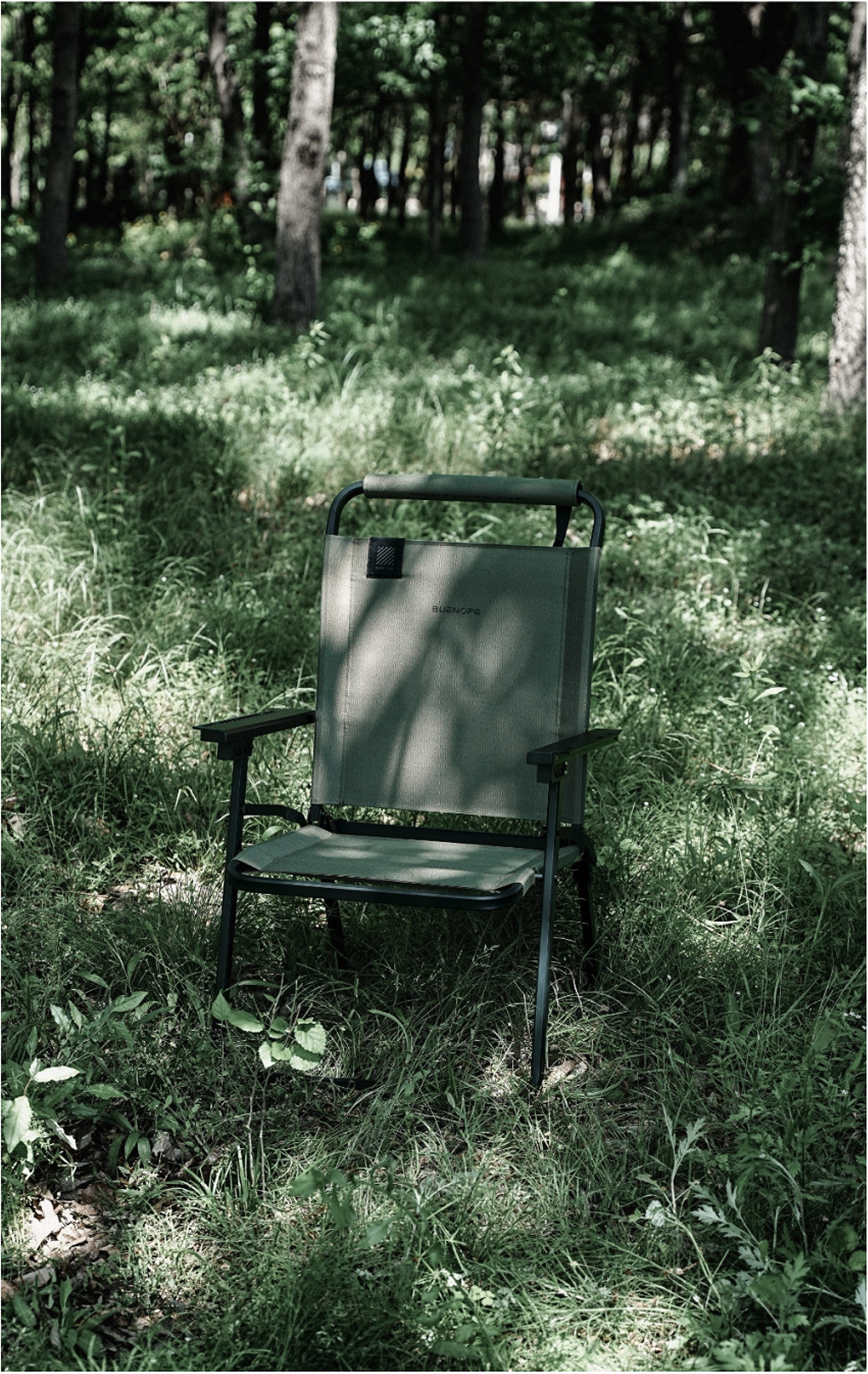 Khaki FLOW folding chair set up on forest grass, front view