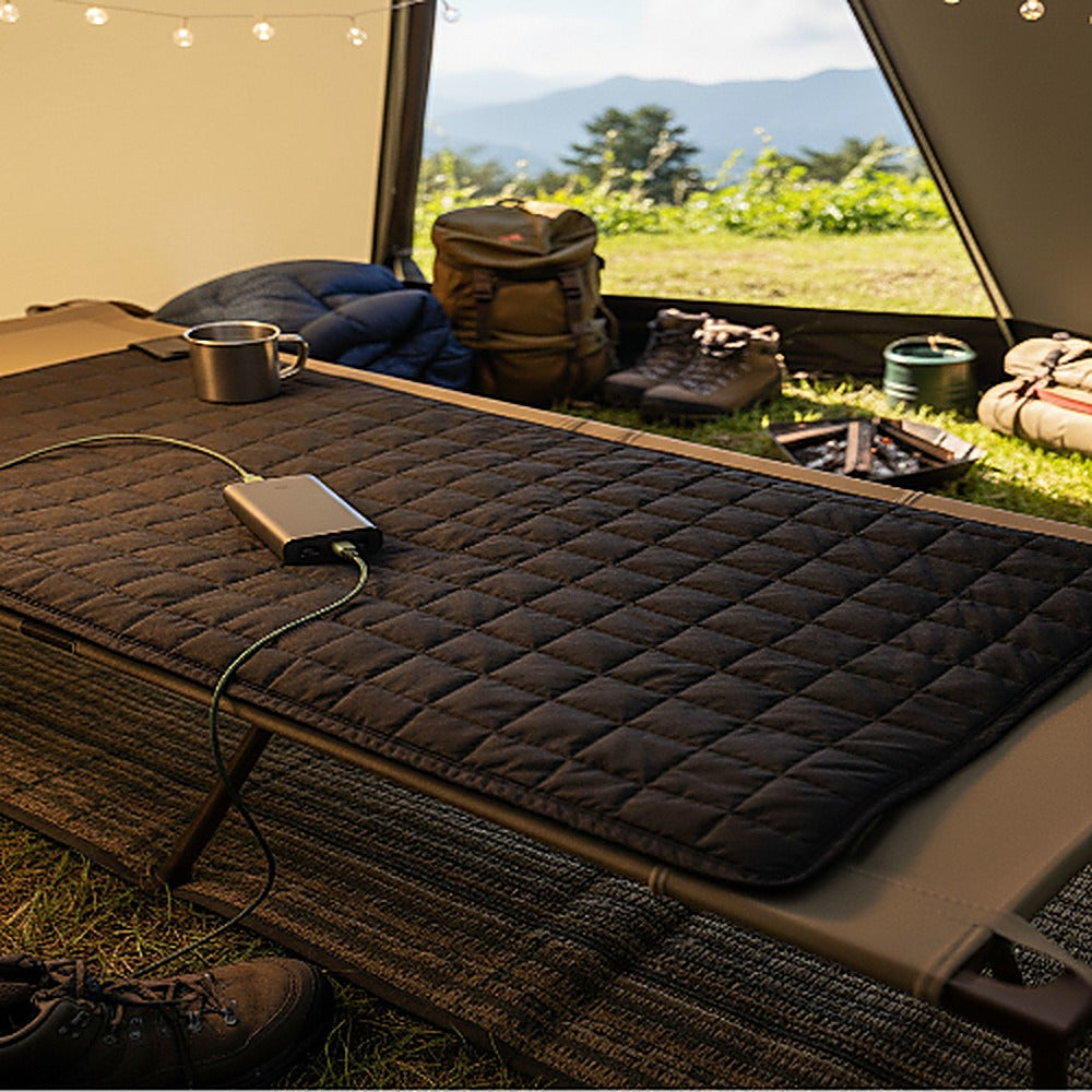 Carbon Heating Pad Large on a camp cot inside a tent, connected to a portable power bank.
