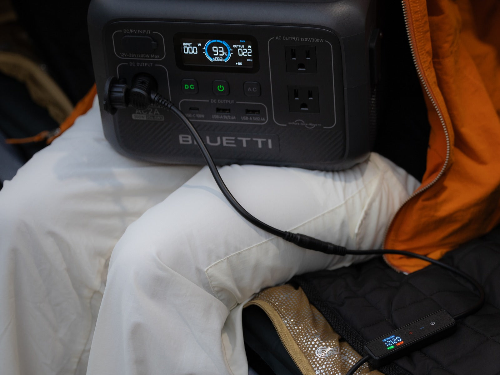 The Carbon Heating Pad Large and its controller on a camp cot, connected through its 12V adapter to the DC output of a portable power station.
