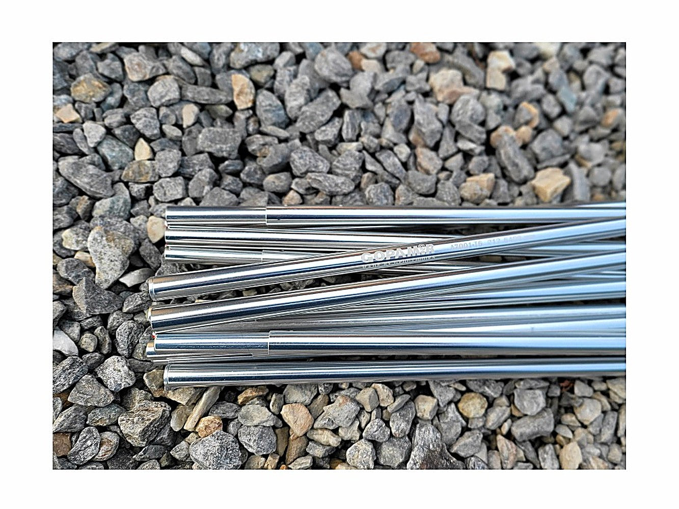 Polished duralumin tent pole segments laid on gravel, GOPAMIR and A7001-T6 etched on the shaft