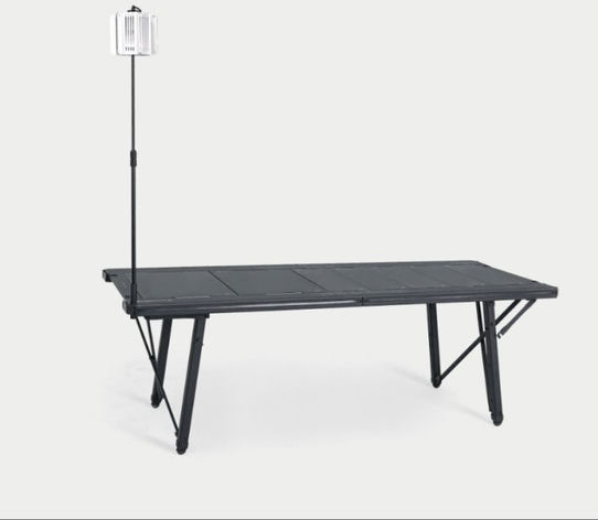 BUENOFE IGT Lantern Hanger set up with a single tall vertical pole and lantern at the end of a long folding aluminum table, shown three-quarter on a soft gray studio background to show placement on a larger table.