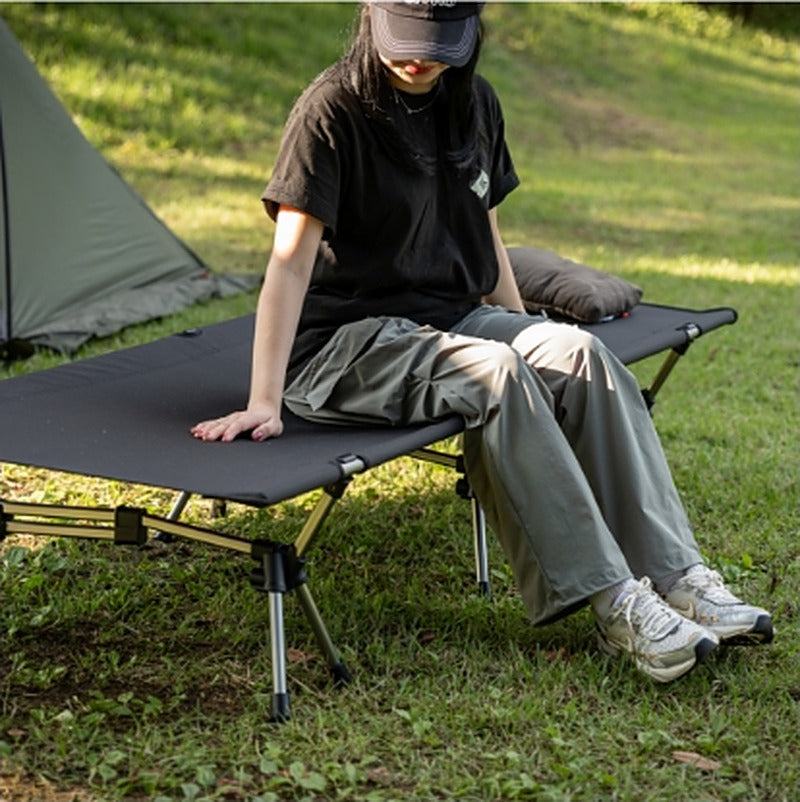 Person sitting on the cot outside a tent