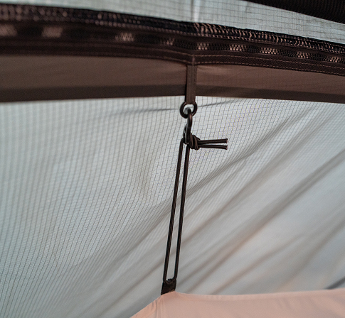 Close-up of a toggle and hook suspension point securing the inner tent's mesh to the shelter frame