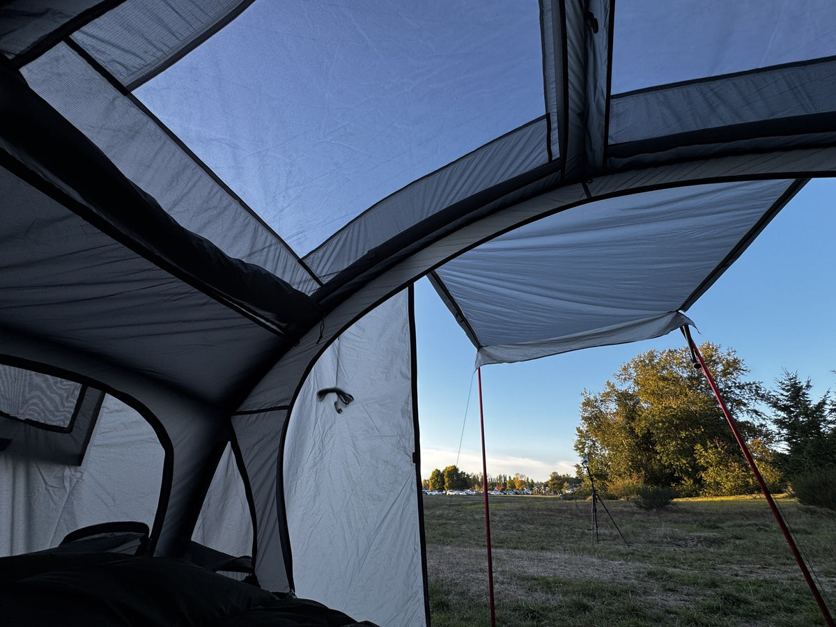View from inside the tent under the Air rainfly awning, door poles framing the field (tent, cot and poles sold separately).