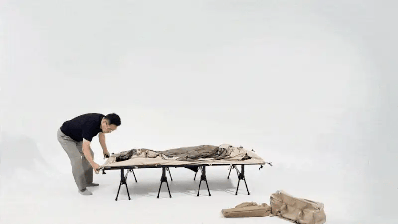 Packing sequence: the Neo Nest 80 tent is folded down onto a camp cot and rolled into its carry bag.