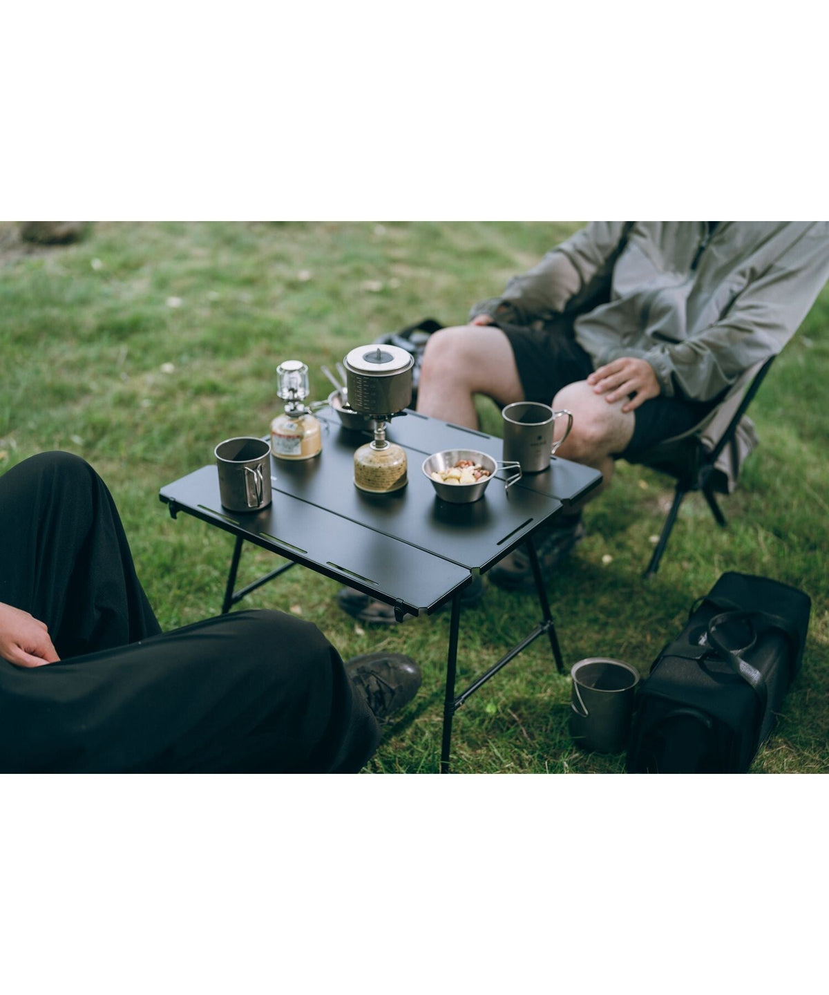 Noga Table, Black, set up on grass between two camp chairs