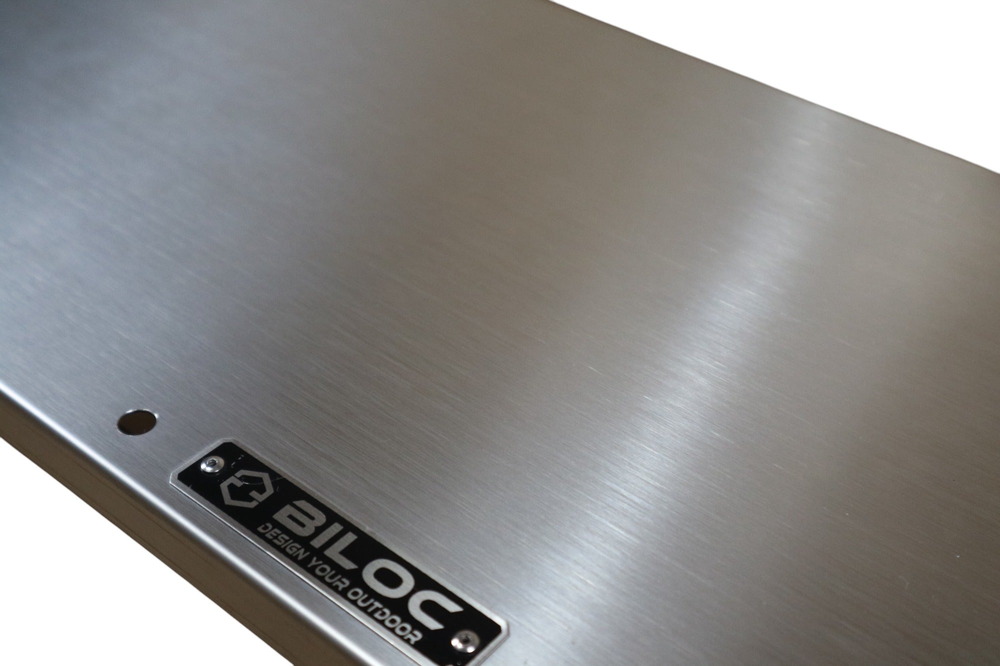 Macro of the brushed 201 stainless plate surface with the BILOC badge.