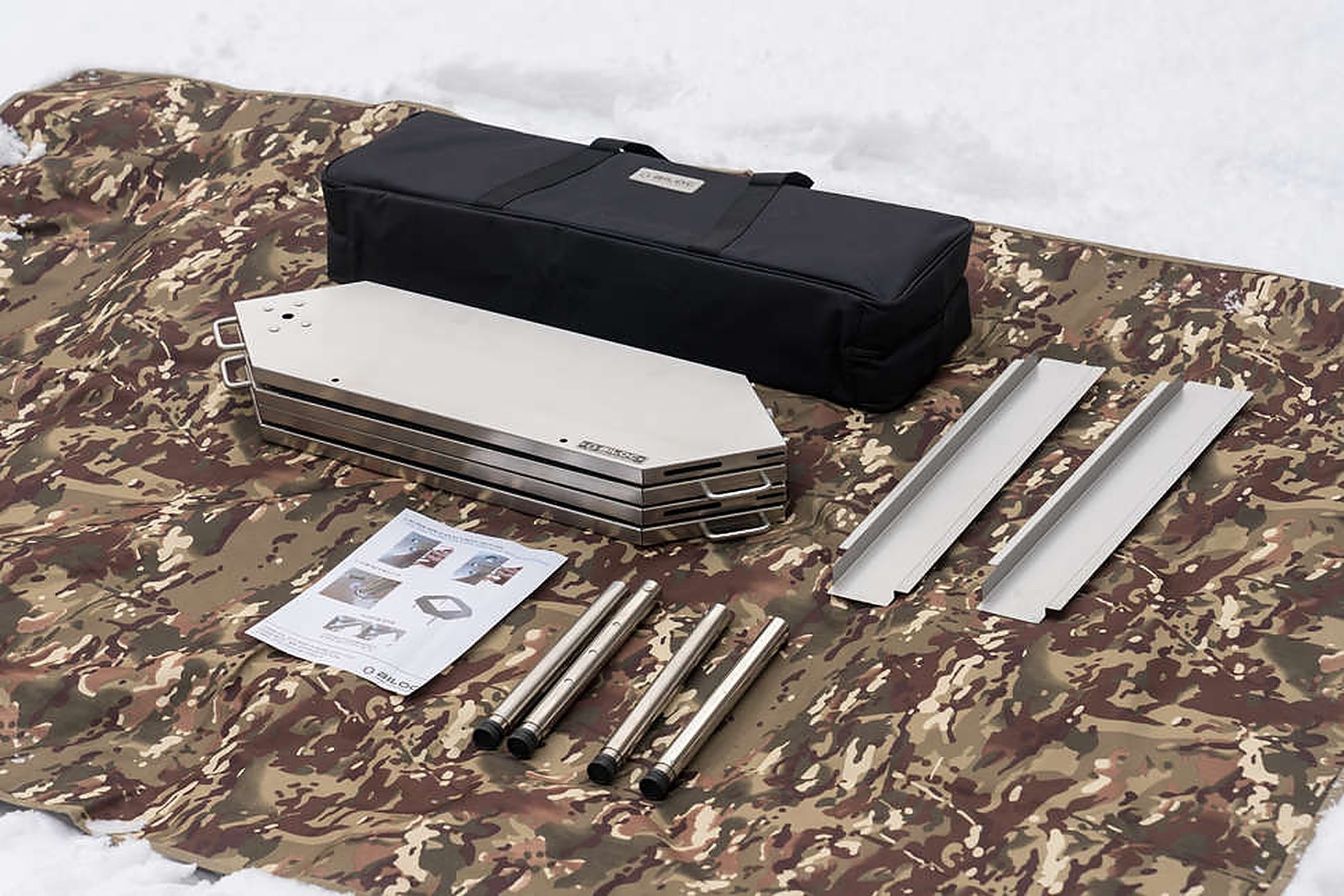 Everything included in the box laid out on a mat: four hinged table plates folded flat, the two-piece inner table set, four legs, the instruction sheet and the padded carry bag.