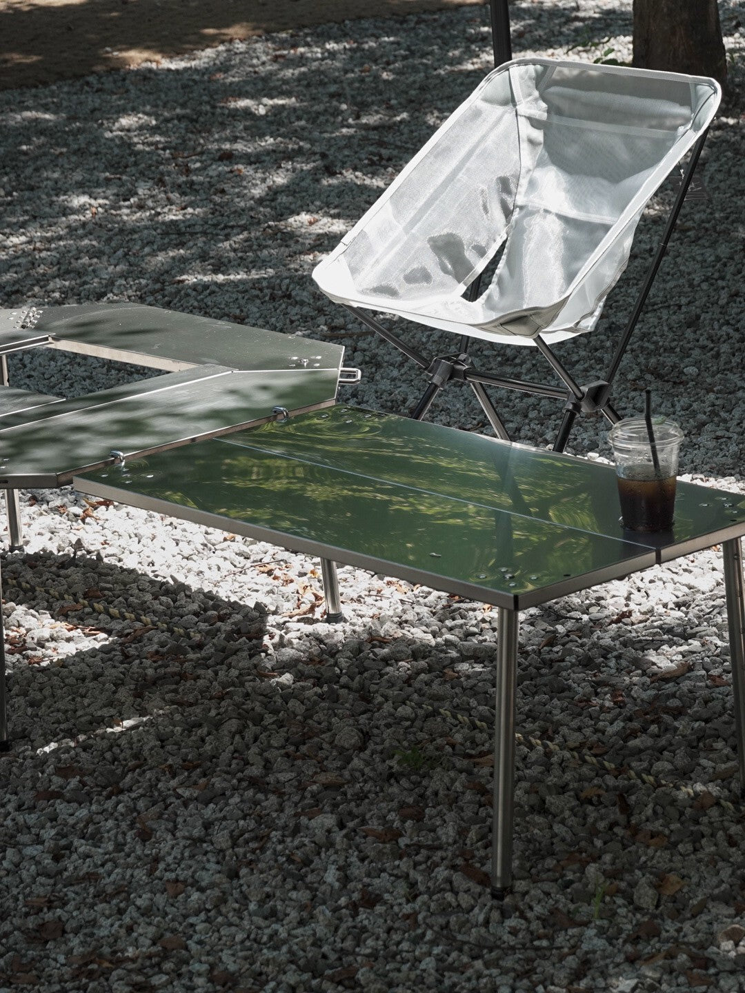 Silver Biloc Ribera table with camp chair and drink at a shaded campsite