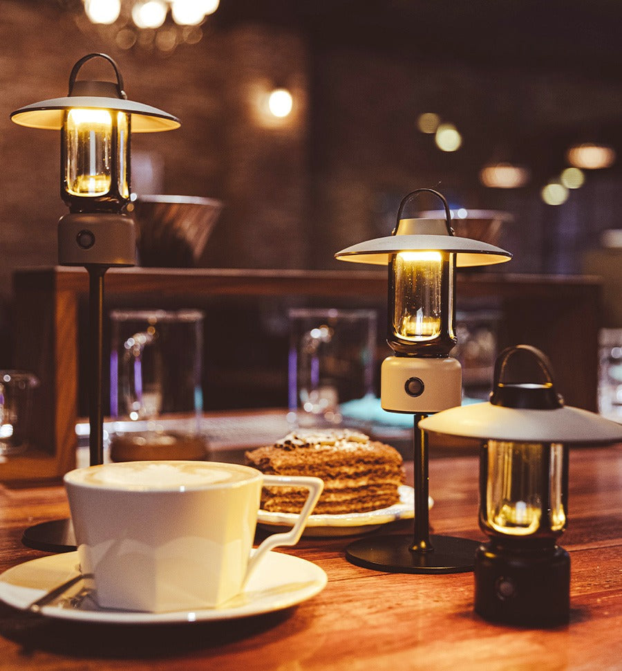 Rico Lantern lit on a cafe table beside coffee and cake