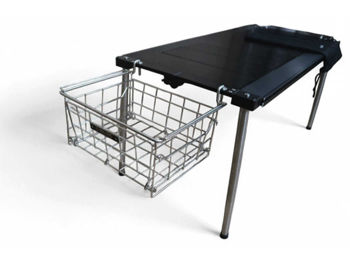 Wire basket hanging from a side hanger below a camp table edge, clear of the work surface.