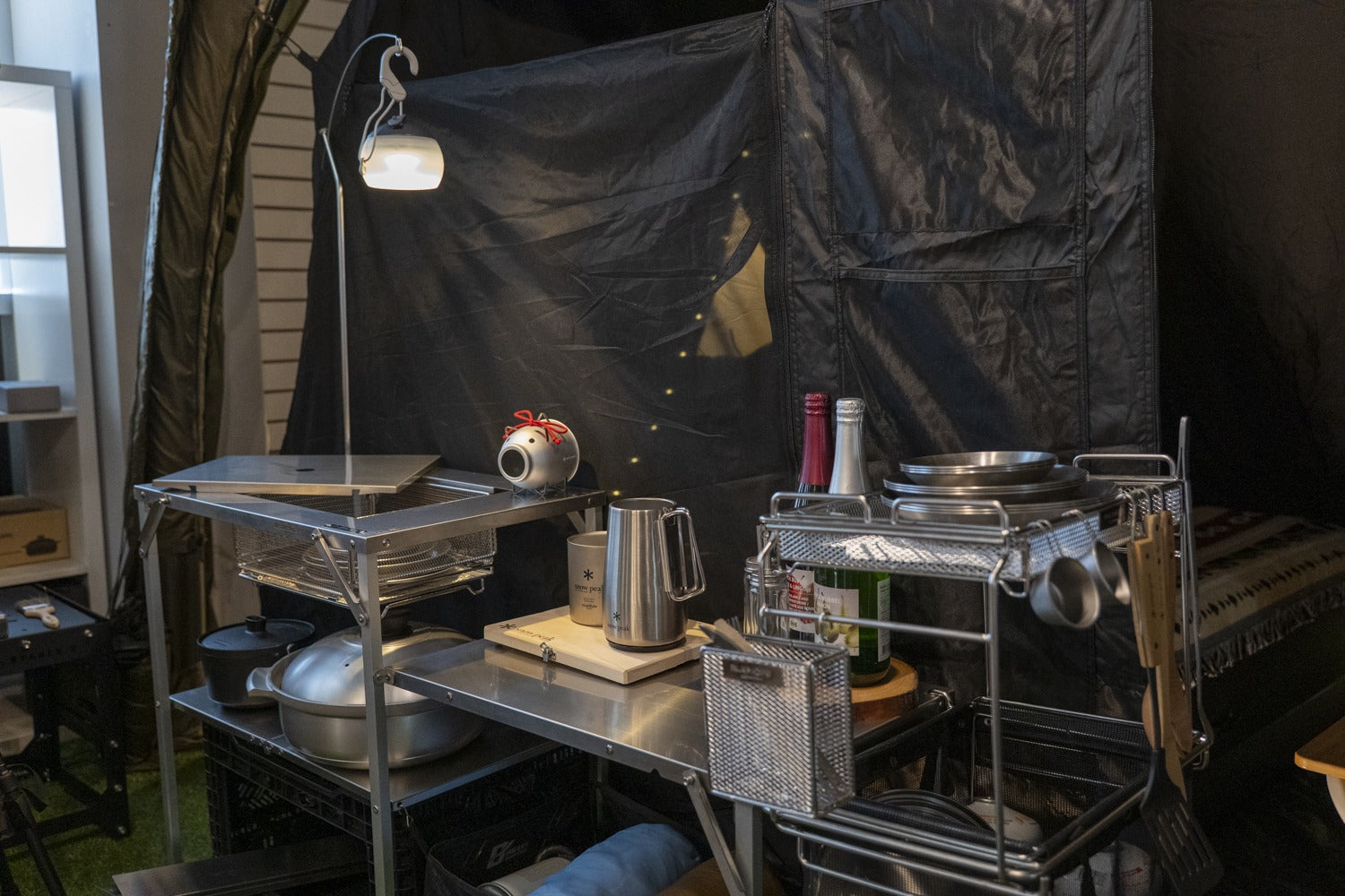 Stella shelf kitchen set up under a lamp arm inside a shelter, loaded with cookware. The lamp, gear and props shown are not included.