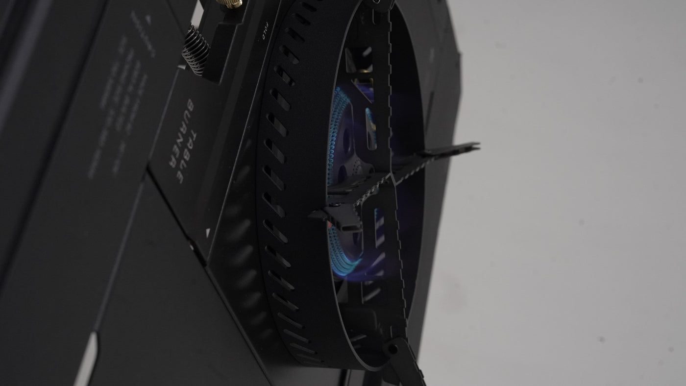 BUENOFE Stove Windscreen viewed from the side with the BX-09 Table Burner lit, showing a blue flame burning steadily inside the vented ring to demonstrate wind-shielded combustion.
