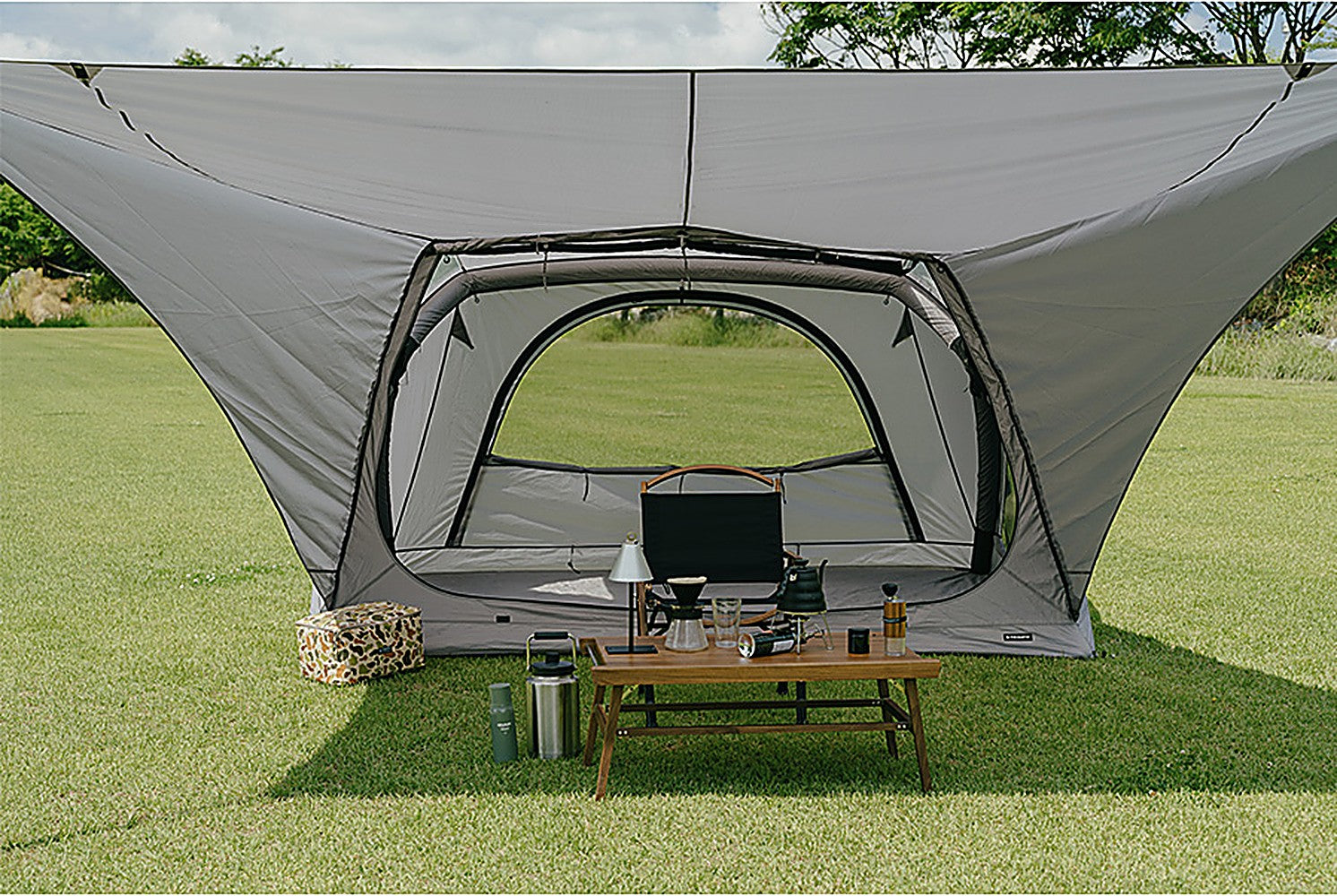 Front-on view of the wide shaded living area under the sun shade with a table and chairs set up beneath it