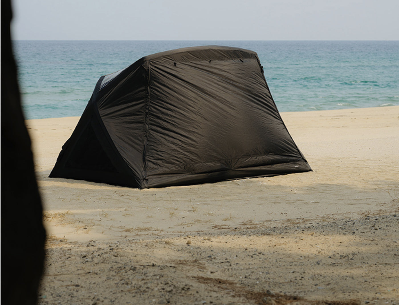 theEarth GEO AIR4 Tent, Black, low side profile pitched on a sandy beach