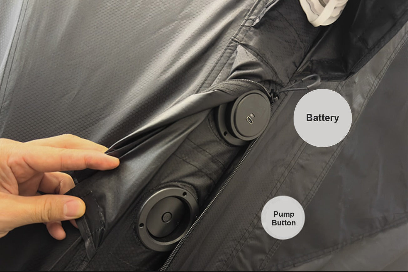 Close-up of hand pressing the built-in pump button at the base of the tent, battery and pump unit visible in pocket