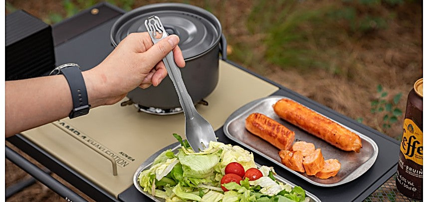 Tongs and grilled sausage on a camp table